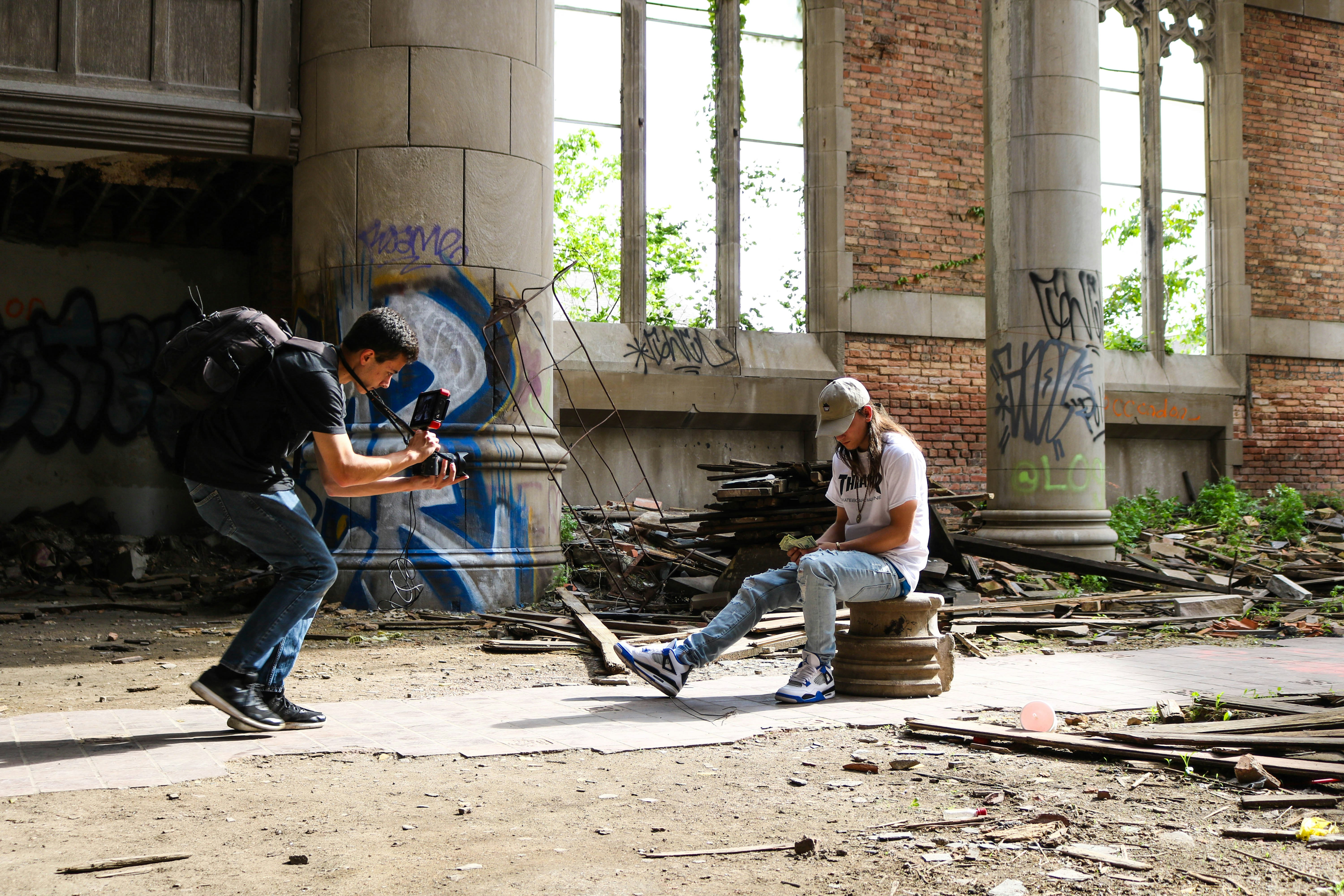 man wearing brown fitted cap sitting near the man holding DSLR camera