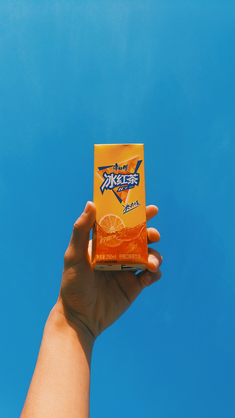 a hand holding a box of orange juice