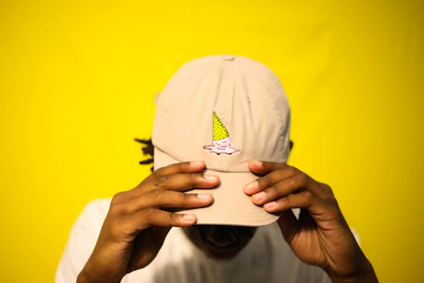 Close-up of a playful yellow butter-tone cap with embroidered logo, styled with casual streetwear.