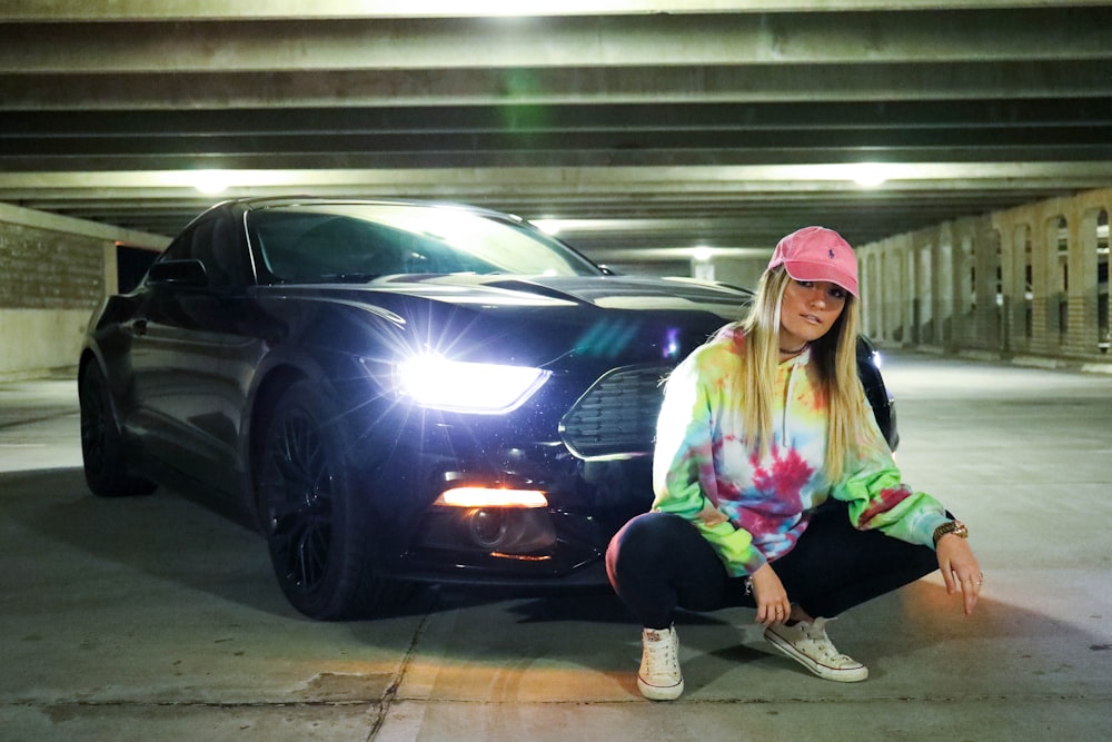 woman sitting beside Mustang coupe