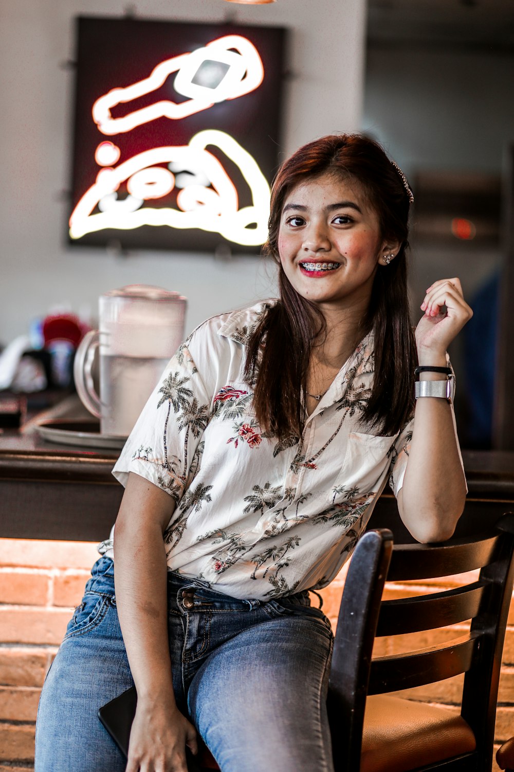 woman wearing gray and red floral blouse sitting on brown wooden barstool