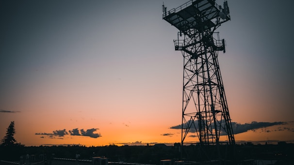 A modern communication tower with digital network overlays at sunset