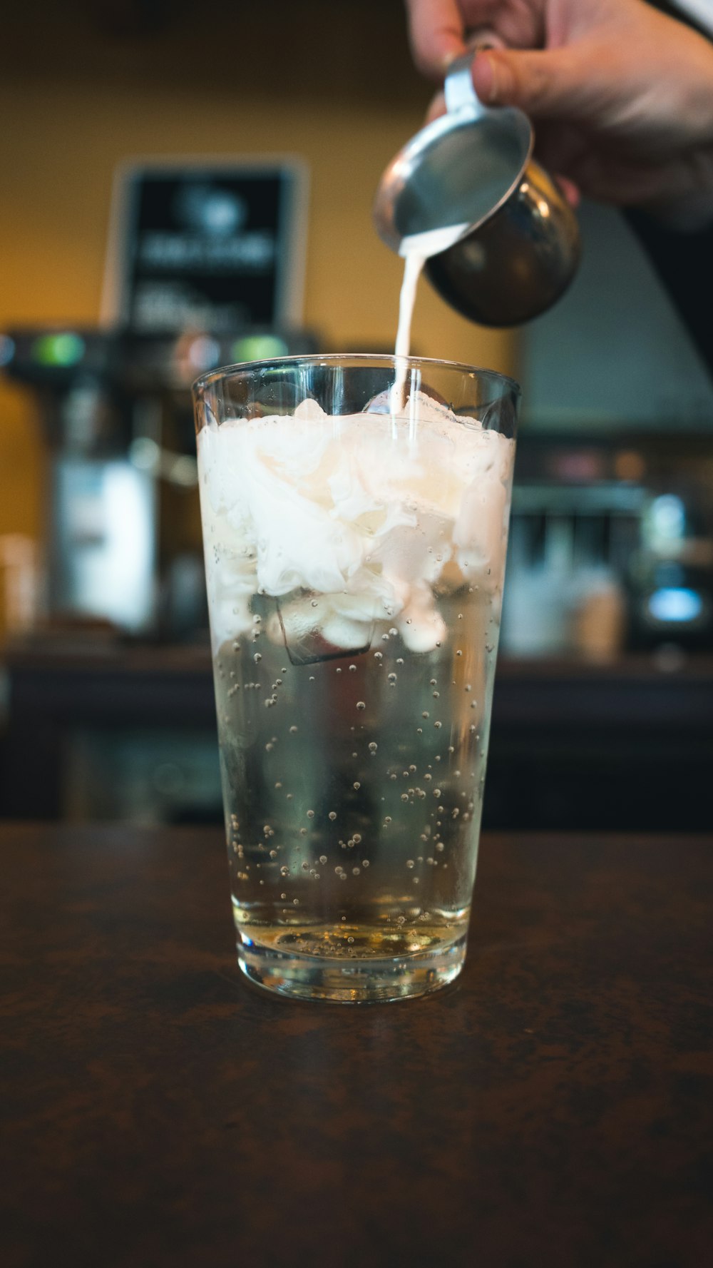 man pouring liquor on glass cup