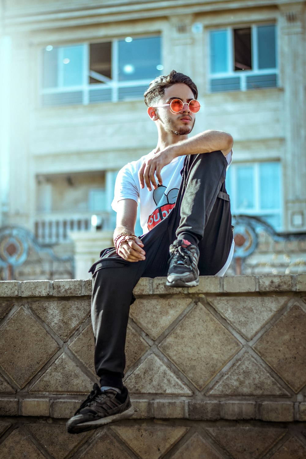 man wearing white crew-neck shirt and gray pants sitting on edge