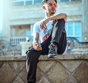 man wearing white crew-neck shirt and gray pants sitting on edge