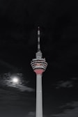 Nighttime photo of a tall antenna tower lit by moonlight against a starry sky.