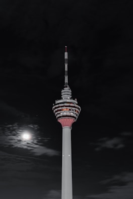 Nighttime photo of a tall antenna tower lit by moonlight against a starry sky.