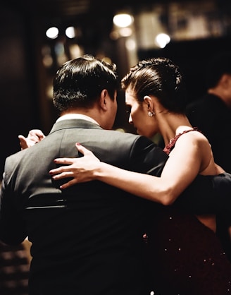 man wearing balck suit jacket and woman wearing red dress dancing