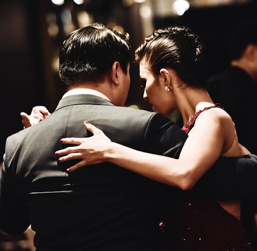 man wearing balck suit jacket and woman wearing red dress dancing