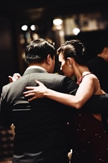 man wearing balck suit jacket and woman wearing red dress dancing