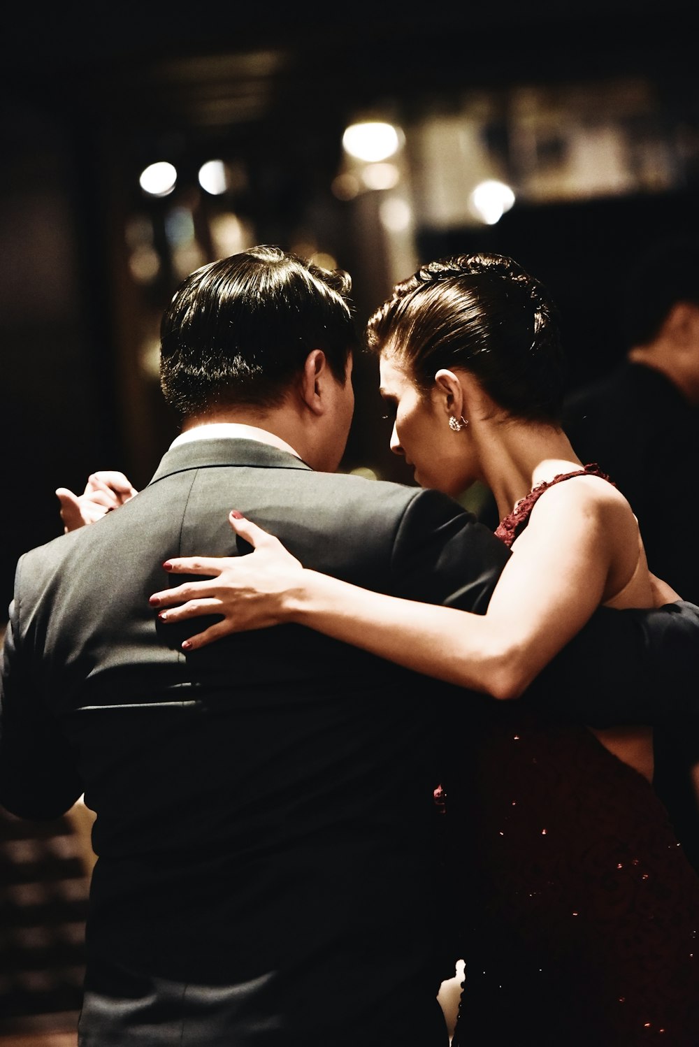 man wearing balck suit jacket and woman wearing red dress dancing