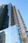 Contemporary high-rise building with glass facade reflecting the blue sky.