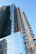 Contemporary high-rise building with glass facade reflecting the blue sky.