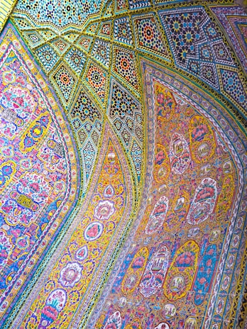 Intricate and colorful mosaic patterns cover the arched ceilings and walls, featuring detailed floral and geometric designs. The artwork combines vibrant hues and ornate craftsmanship, reflecting traditional art styles.