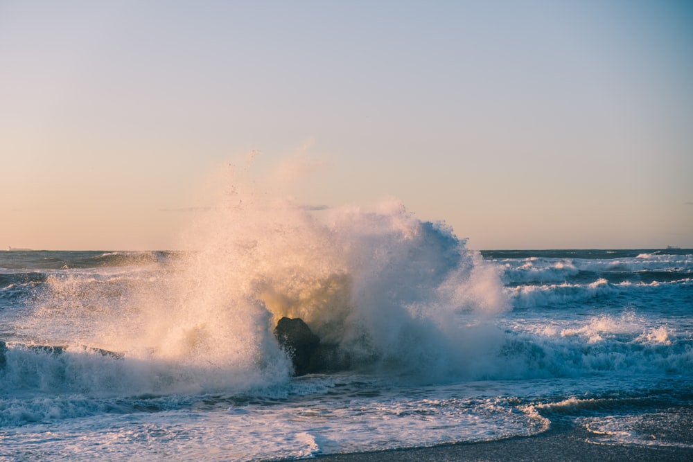 a large wave crashing into the shore of a beach