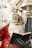 A festive Santa Claus statue holding a book is adorned in a classic red and white outfit, with shiny bells hanging above. The intricate details on Santa’s face and beard, along with the gloved hand holding the book, are well-defined.