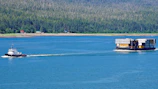 A tugboat guiding a massive container ship through calm waters.