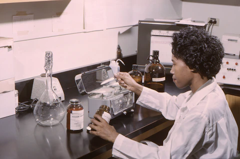 woman lab tech sitting in front of black table with DNA DRUG samples