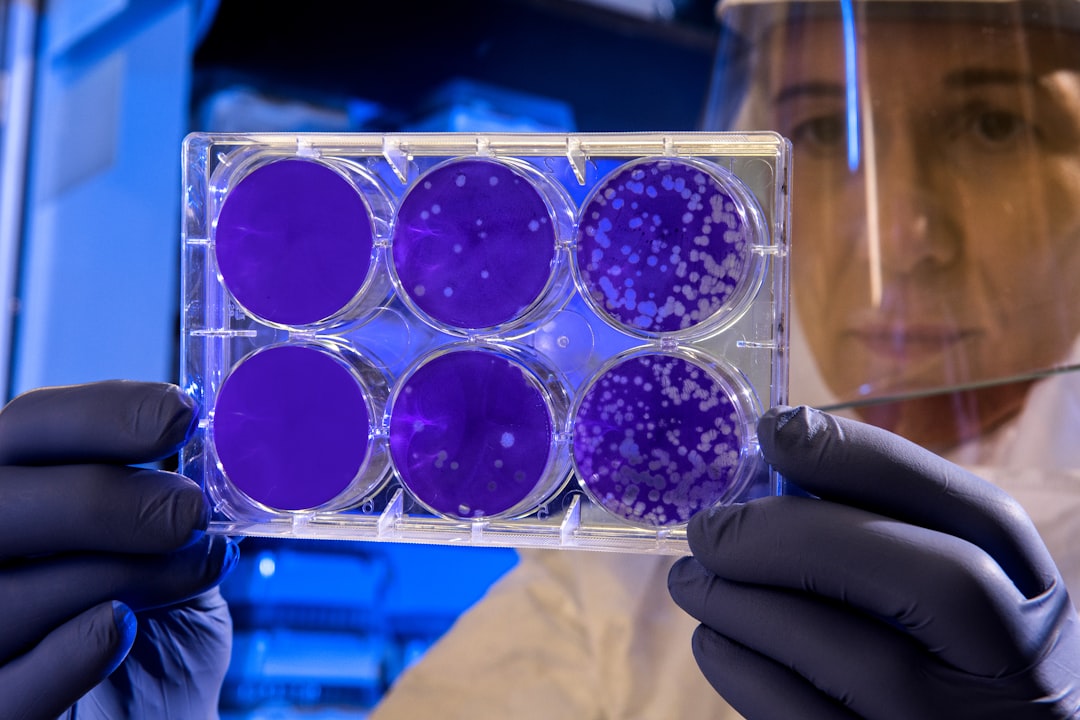 woman holding a tray of petri dishes, some contain growing colonies.