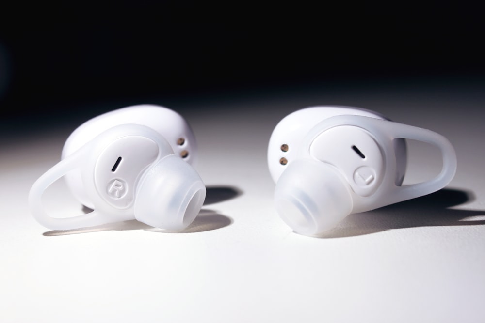 pair of white wireless earpieces on white surface