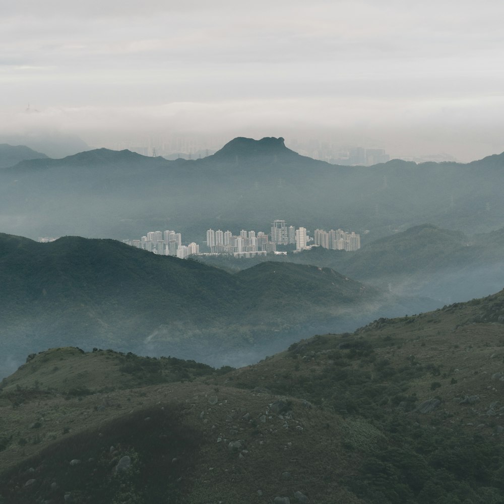 city buildings in front of green and brown mountain peak