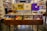 A well-organized record store display featuring a variety of vinyl albums. The records are neatly arranged in wooden bins, categorized by genre with visible labels such as 'Rock' and 'Psych/Prog'. The album covers visible feature a mix of vibrant and subdued artwork, suggesting a diverse collection. The store's interior is dimly lit, with more records lining the walls in the background.