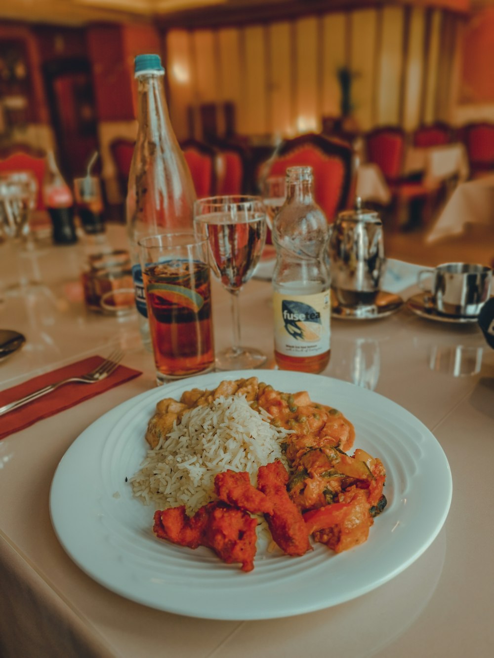 cooked rice with fried food on round plate near bottles on table