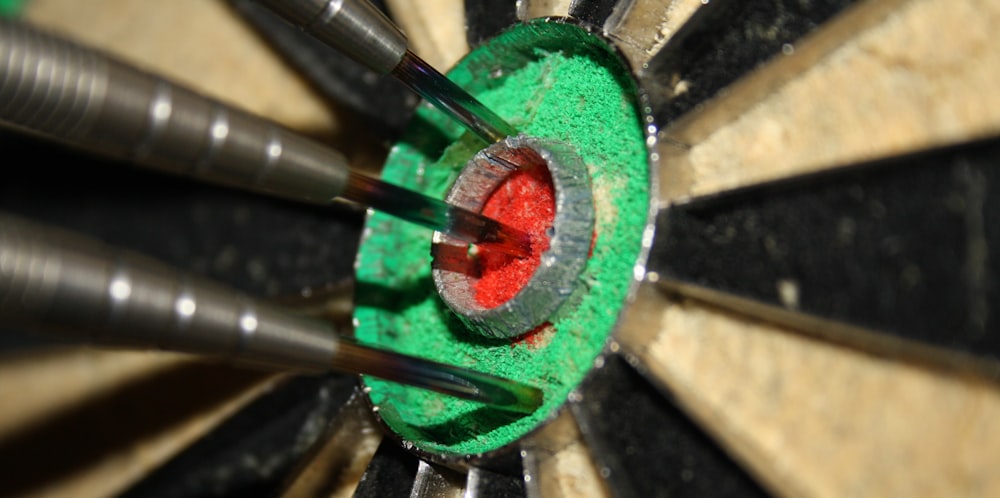 three gray pens on green and red surface