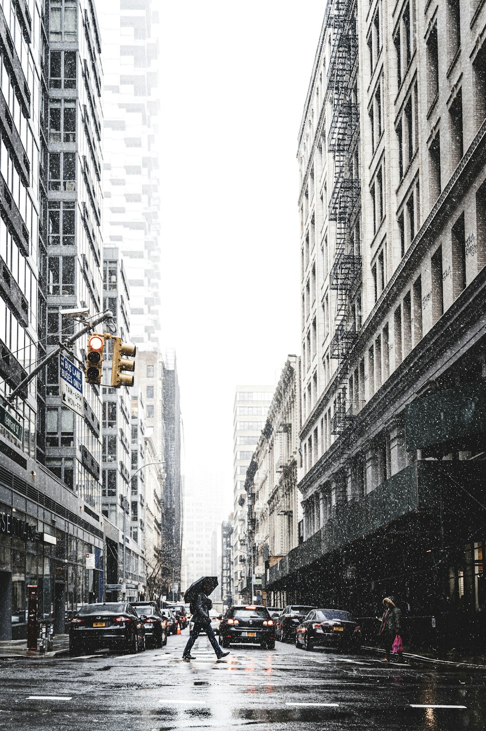 a person with an umbrella crossing a street in the rain