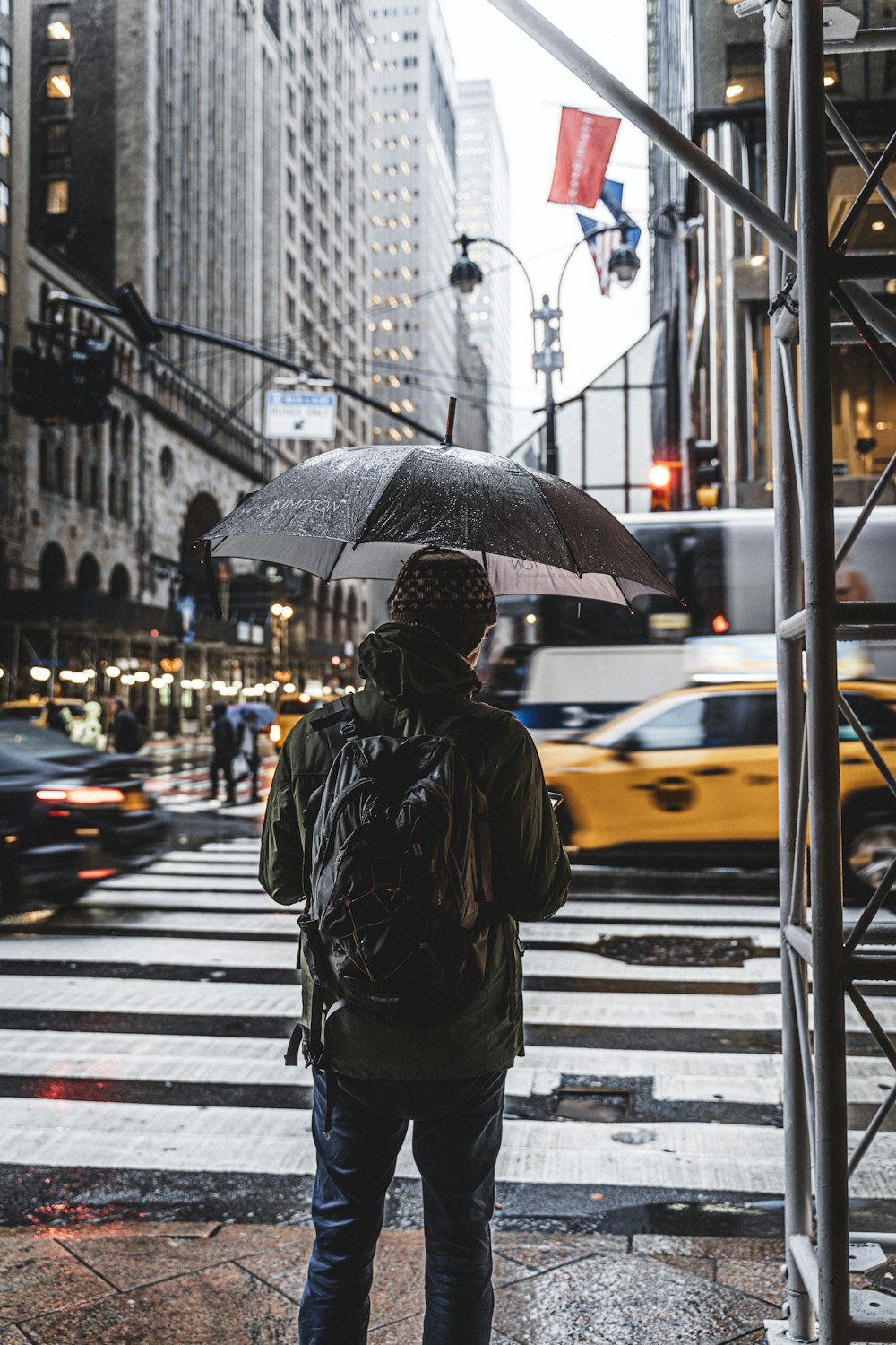 man in black jacket waiting beside crosswalk