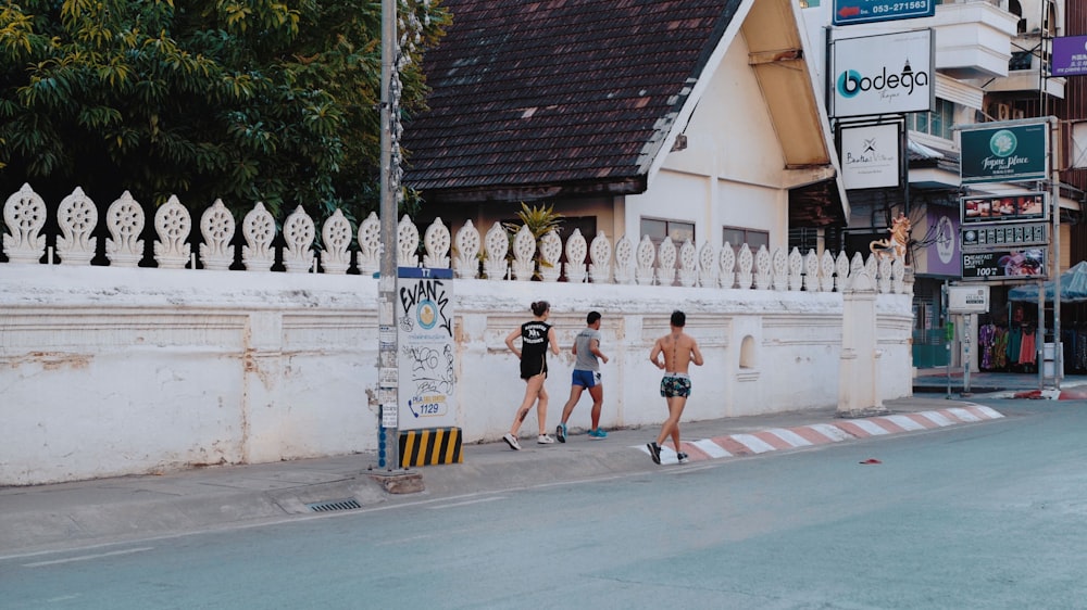 three men jogging on sidewalk