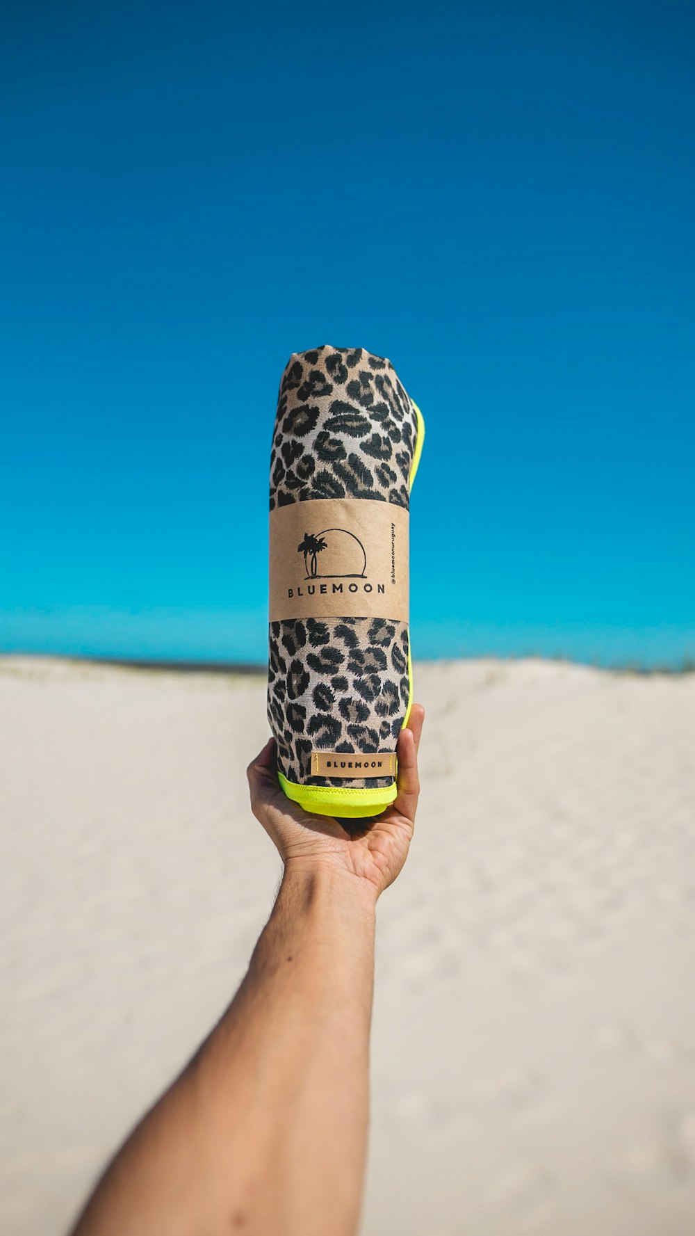 a person holding up a bottle in the sand