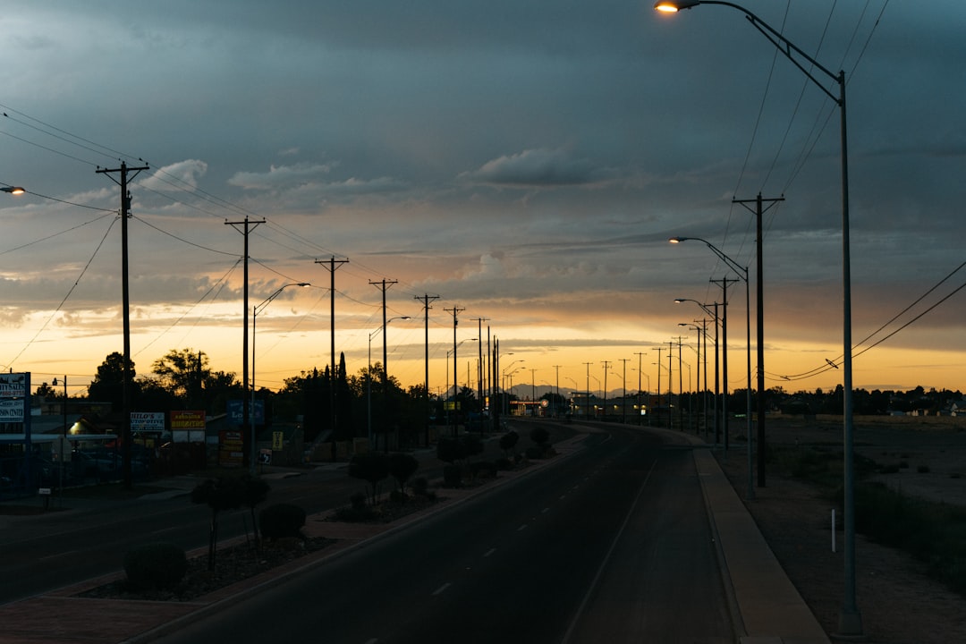 street lights and power poles lining a deserted road with the sun setting