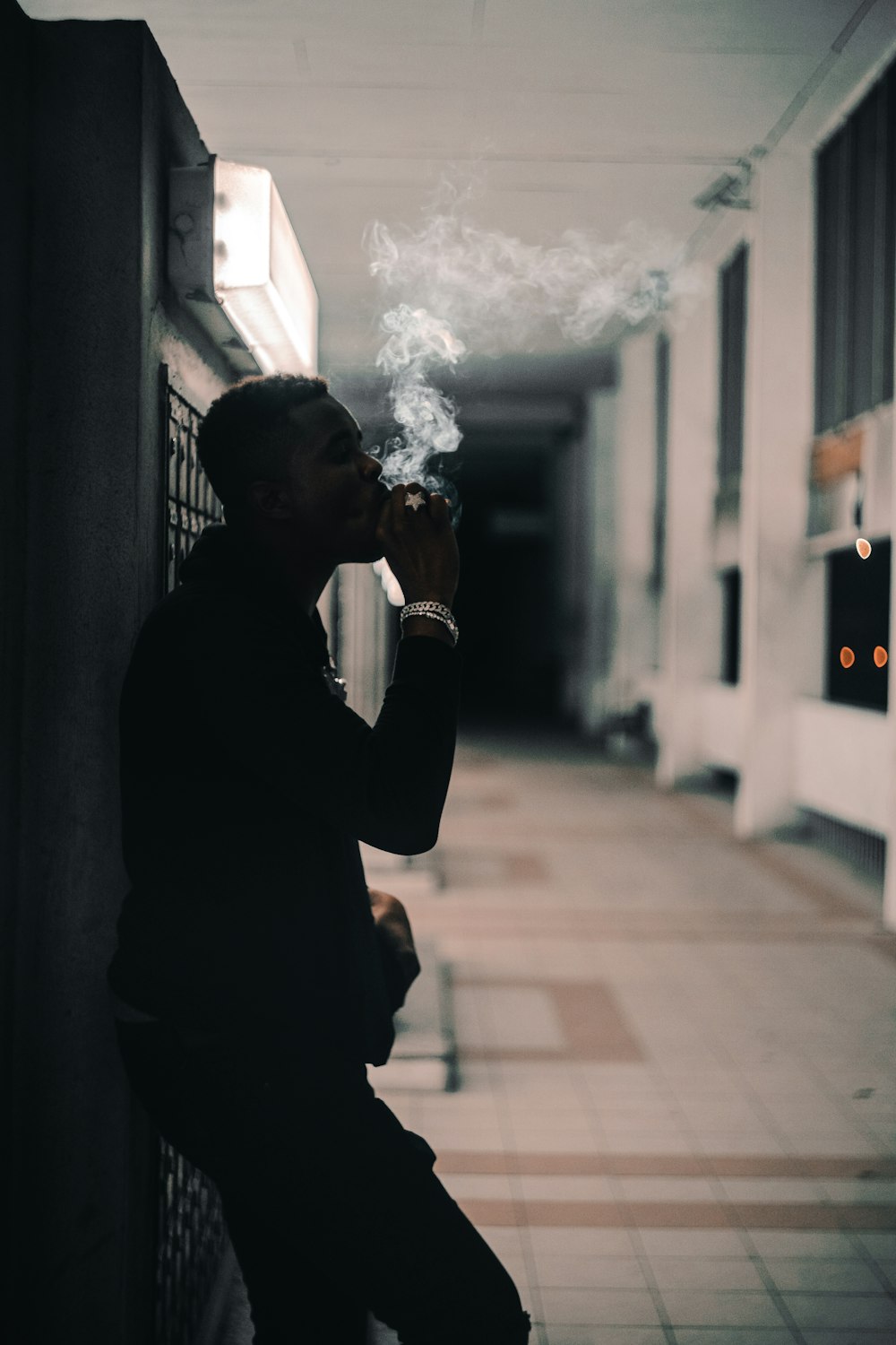 photography of smoking man while leaning on wall