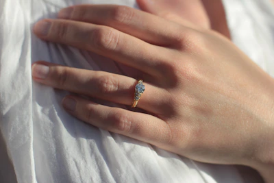 Illustration of a hand gently placing a ring on the screen with soft golden light highlighting the sizing process.