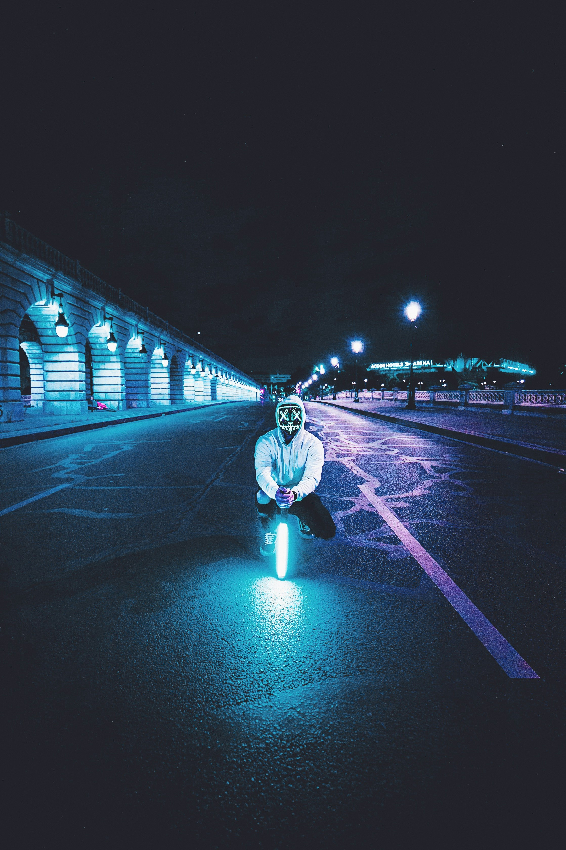 man squatting on asphalt road holding LED light