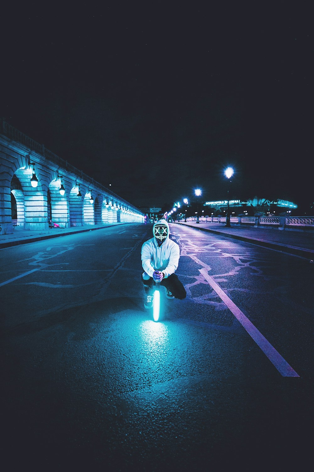 man squatting on asphalt road holding LED light