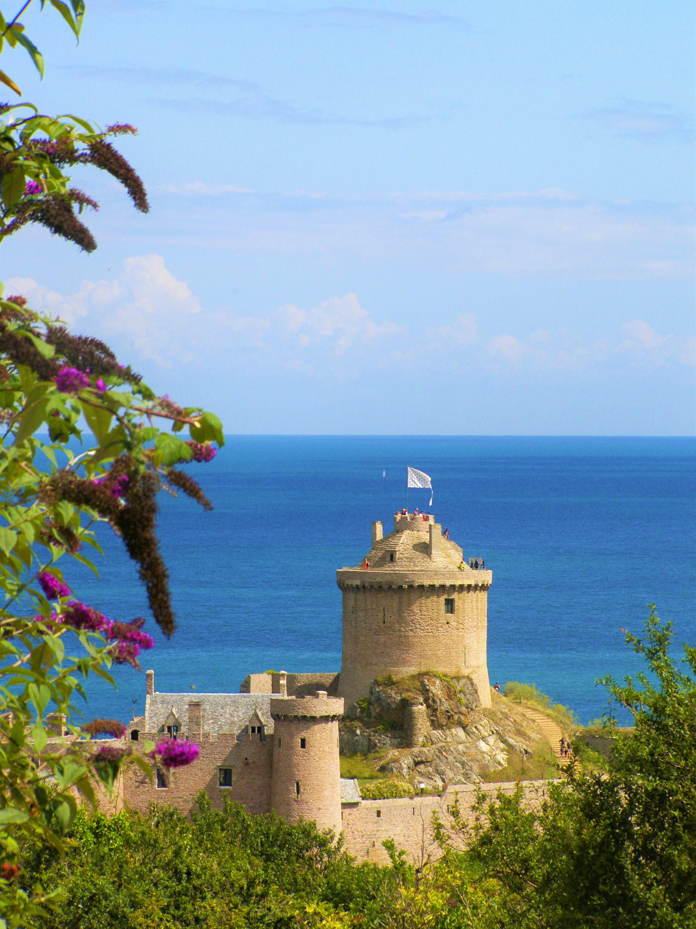photography of brown building beside seashore during daytime