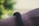A close-up of a person's wrist wearing a black, textured fitness band. The background is blurred with greenish hues, suggesting an outdoor setting.