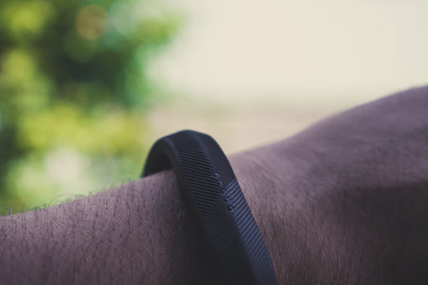A modern fitness tracker wrapped around a wrist during a morning jog in the park.
