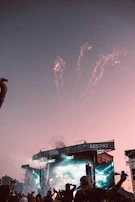 A panoramic shot of a concert stage with 3D mega stage setup and fireworks bursting in sync with music.