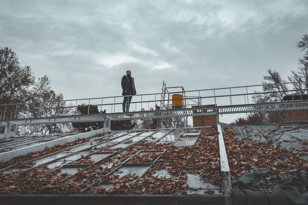 low-angle photography of man standing on metal bridge during daytime