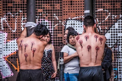 two men tied on poles tattoo teams background