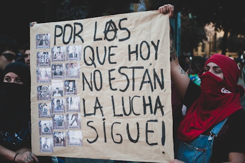Close-up of hands holding a photo collage of victims and protest scenes.