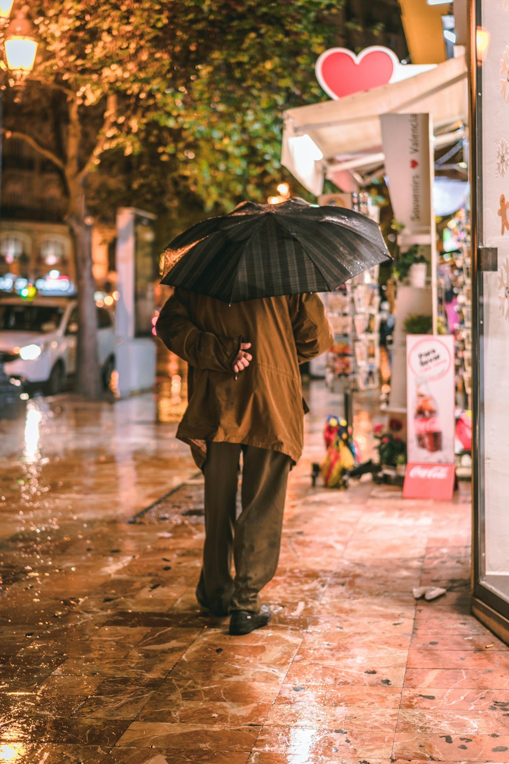 person with umbrella walking on sidewalk