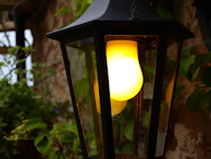 Close-up of a sleek LED solar luminaria glowing warmly at dusk in a garden.