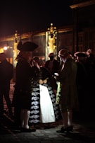 Guests dressed in period attire mingling under soft, golden lighting at a book launch.