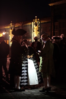 Guests dressed in period attire mingling under soft, golden lighting at a book launch.