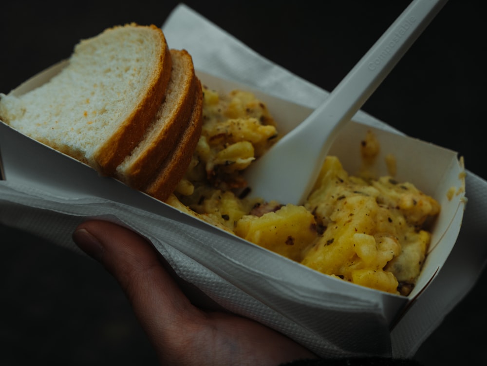 a person holding a sandwich in a paper container