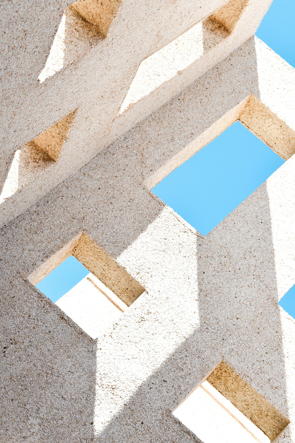 an abstract photo of a concrete structure with blue sky reflected in it